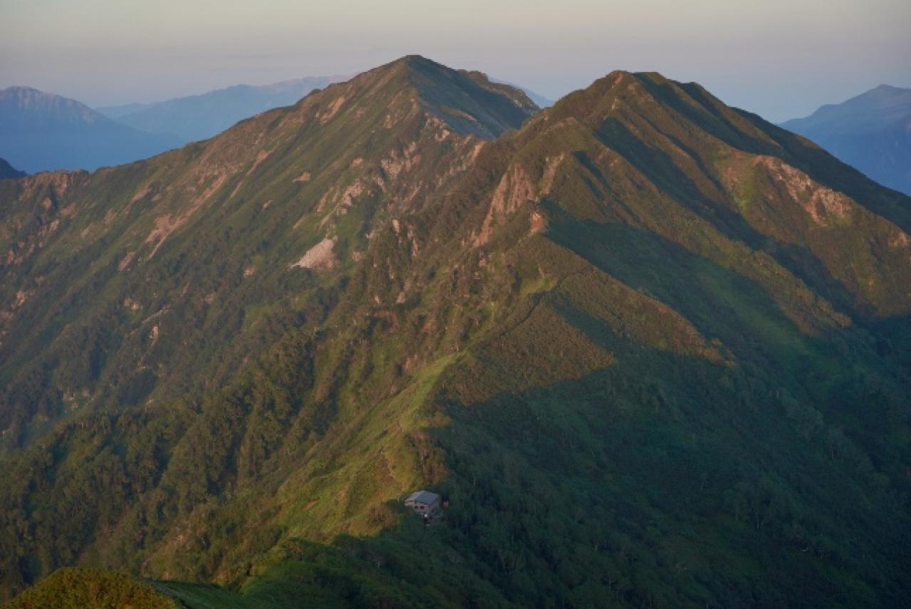 朝の新越山荘と鳴沢岳と赤沢岳。奥には薬師岳が横たわる。